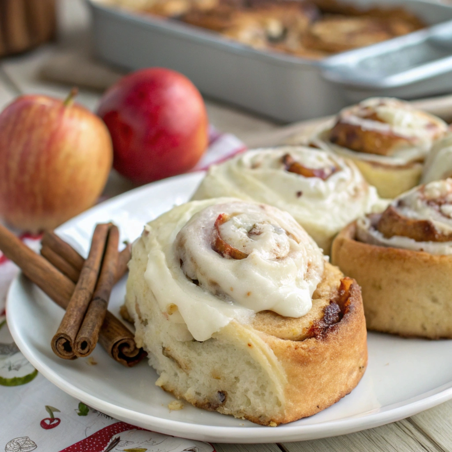 Apple cinnamon rolls with brioche dough topped with cream cheese frosting, served on a white plate