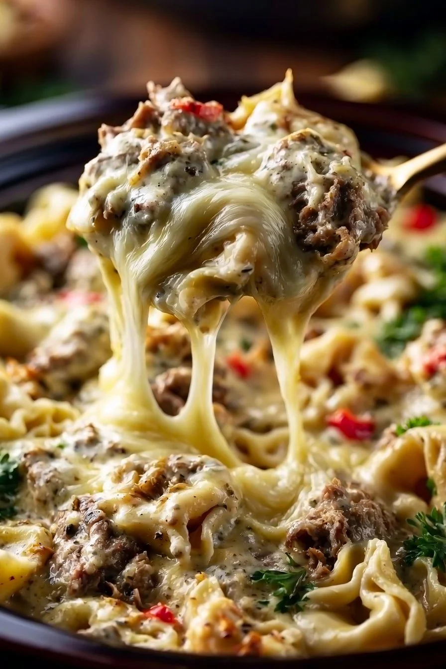 Cheesesteak tortellini dish made in a crock pot, showcasing rich flavors and cheesy goodness.